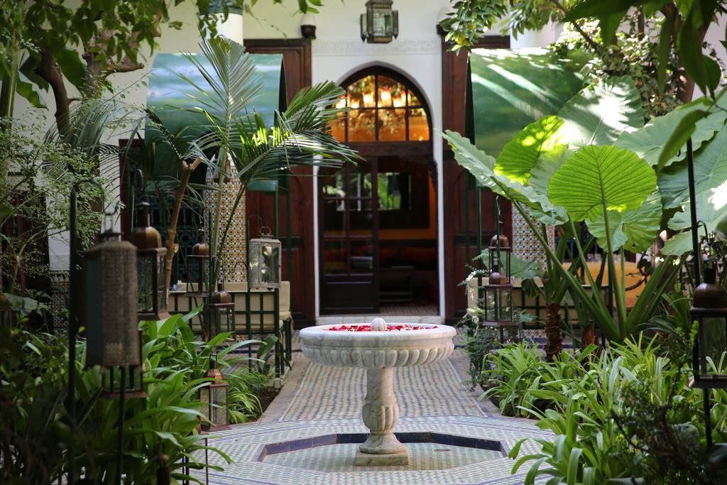 Fontaine aux fleurs dans le jardin luxuriant du Palais Riad Lamrani à Marrakech.