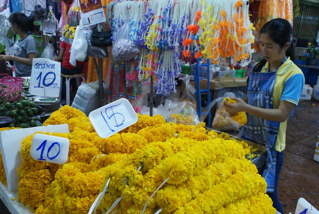 Préparation des couronnes d’offrandes par une ouvrière du marché aux fleurs à Bangkok.