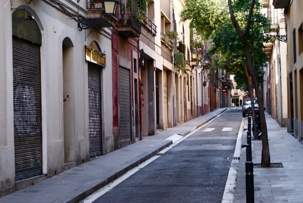 Ruelle typique bordée d’arbres de Gracia avec des immeubles bas.