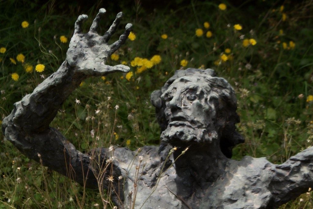 Insolite : La statue sombre dans un lit de fleurs, oeuvre contemporaine du cimetière Certosa de Bologne.