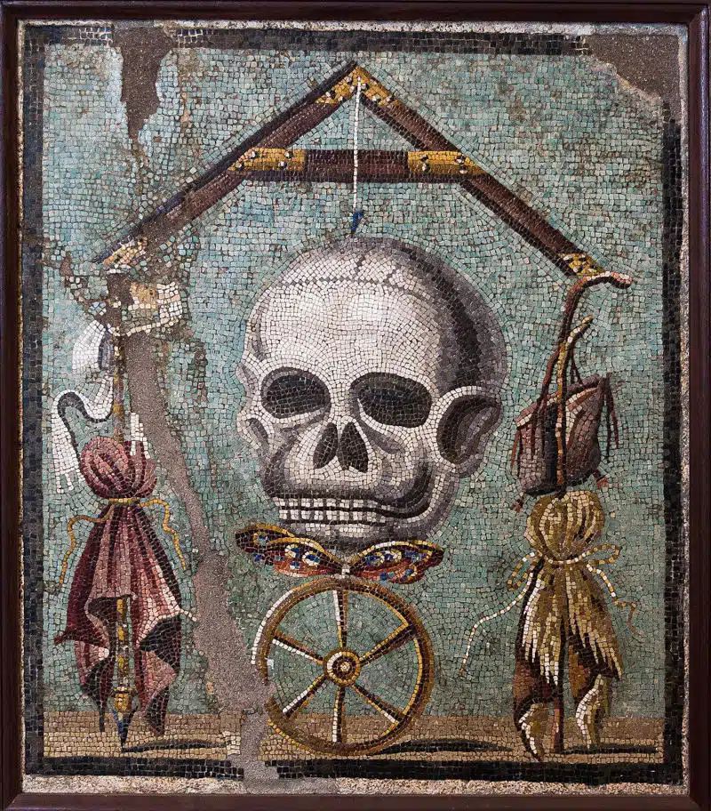 Memento mori ou la roue de la fortune. La mosaïque représente la Roue de la Fortune qui, lorsqu’elle tourne, peut faire du riche (symbolisé par l’étoffe pourpre à gauche) un pauvre, et du pauvre (symbolisé par la peau de chèvre à droite) un riche ; en effet chaque état est très précaire, la Mort est aux aguets à tout moment, et la vie tient à un fil : lorsque ce dernier rompra, l’âme (symbolisée par le papillon) s’envolera. Et tout le monde sera sur un pied d’égalité. Photo de Jébulon