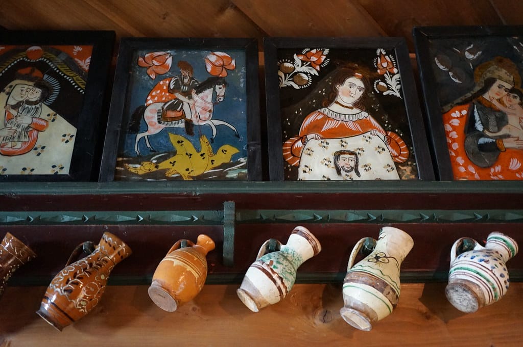 Intérieur d'une maison traditionnelle du Podhale avec peintures sur verre et pots en terre cuite.