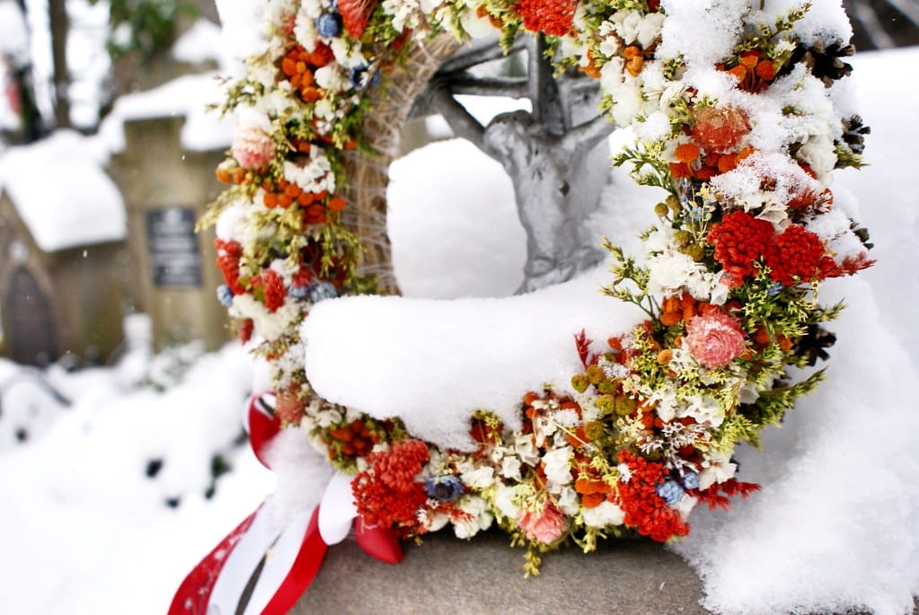 Couronne de fleurs séchées sous la neige dans le cimetière.